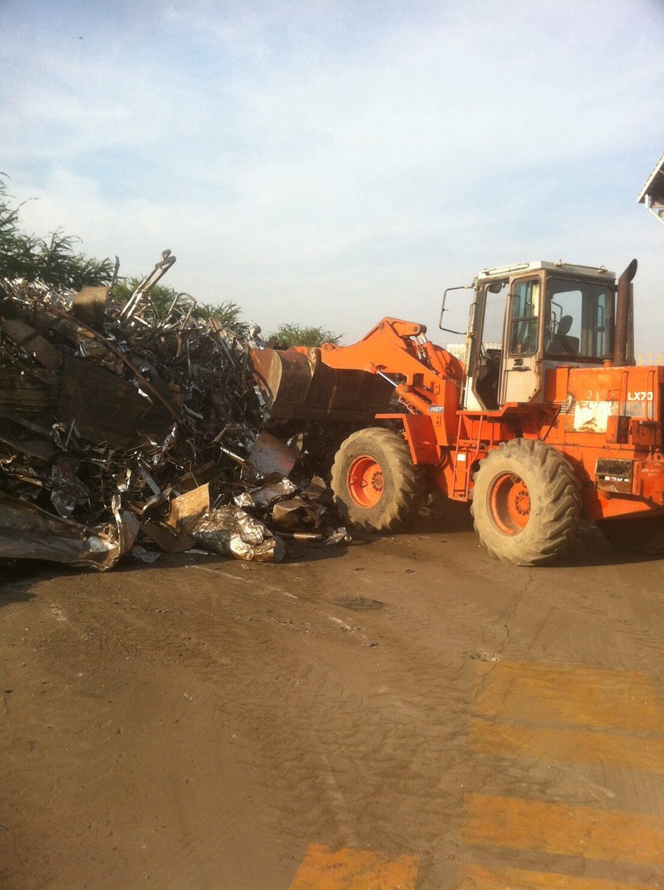 รถตักล้อยาง HITACHI LX70 ของ BIG MACHINE TRADING ตักเศษโลหะใกล้กองเศษอลูมิเนียมในโรงงาน