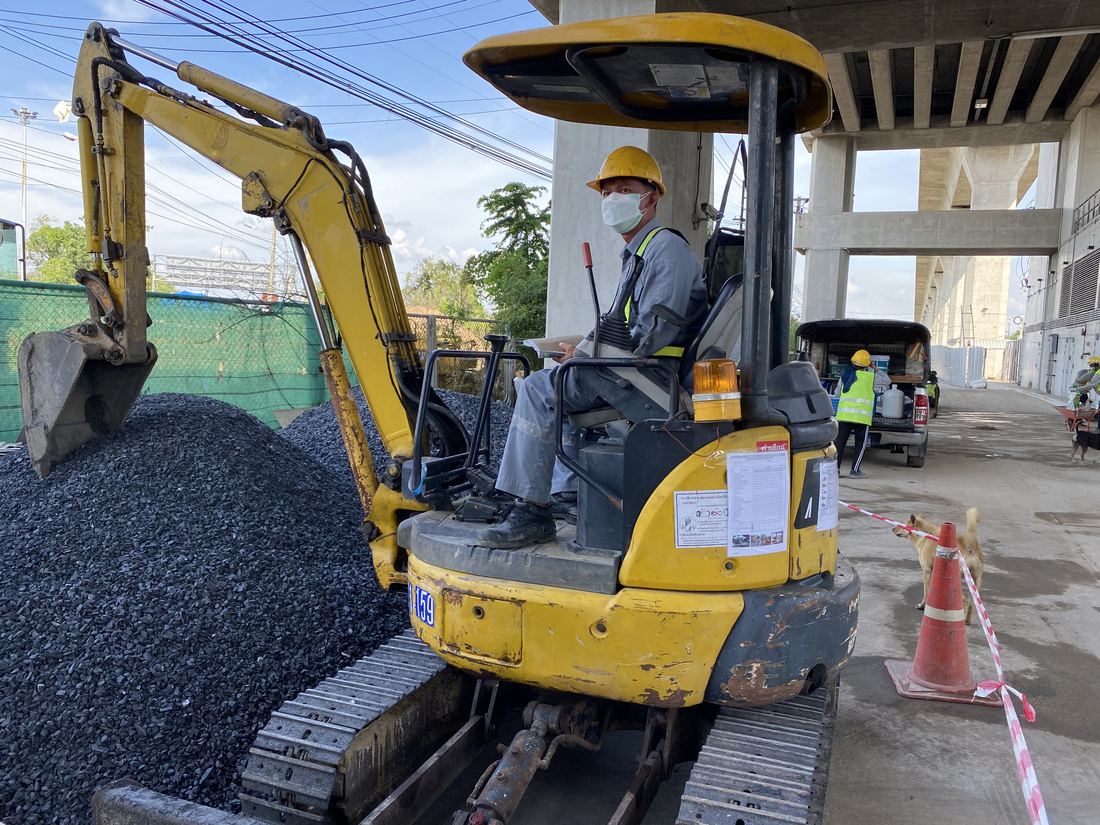 แบคโฮขนาดเล็ก PC30 ของ BIG MACHINE TRADING ตักหินงานปรับปรุงพื้นใต้ทางยกระดับ Airport Rail Link สถานีลาดกระบัง มีกรวยและเทปกั้นแยกพื้นที่ทำงาน