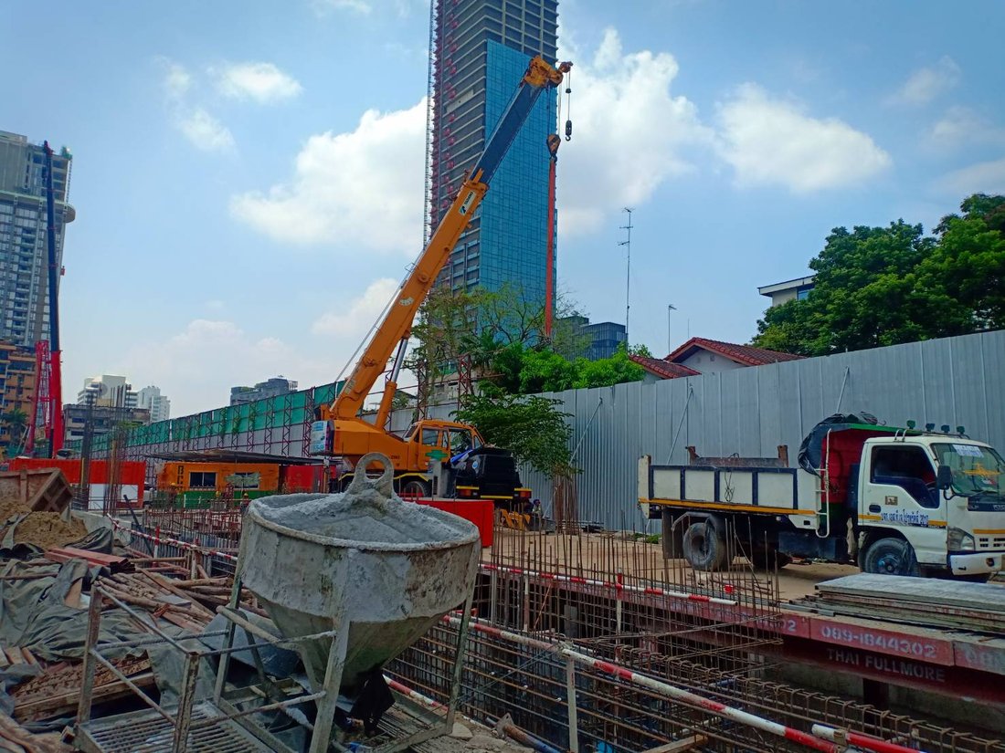 เครนล้อยางสีเหลือง BIG MACHINE TRADING ยกของขึ้นตึกสูงระหว่างก่อสร้างที่ไซต์งานย่านราชดำริห์