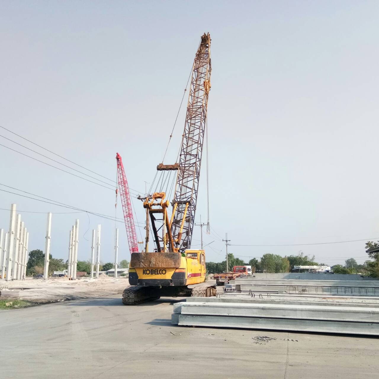 เครนตีนตะขาบ KOBELCO สีเหลืองของ BIG MACHINE TRADING ทำงานที่บ้านบึง ชลบุรี มีเครนตีนตะขาบสีแดงอีกคันอยู่ด้านหลัง