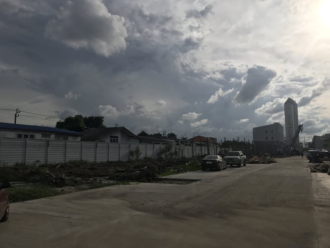 พื้นที่ก่อสร้างโครงการ PLEX BANGNA มีเมฆครึ้มฝนก่อนเข้าหน้างาน มองเห็นอาคารสูงพื้นหลัง