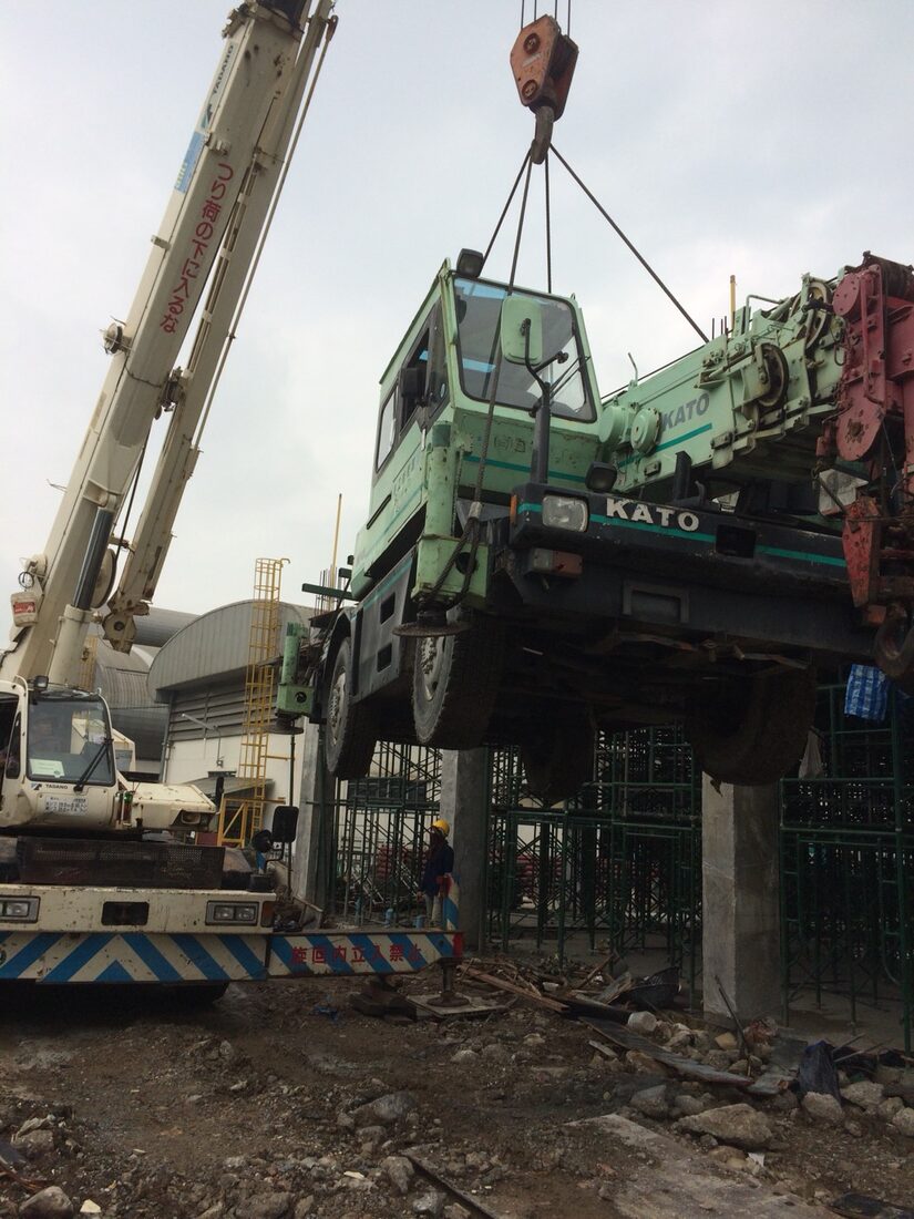 เครนล้อยาง 10 ตัน KATO ของ BIG MACHINE TRADING ทำงานใกล้เหล็กเสริมและเสาคอนกรีตในพื้นที่ก่อสร้างที่จำกัด นิคมบางปู