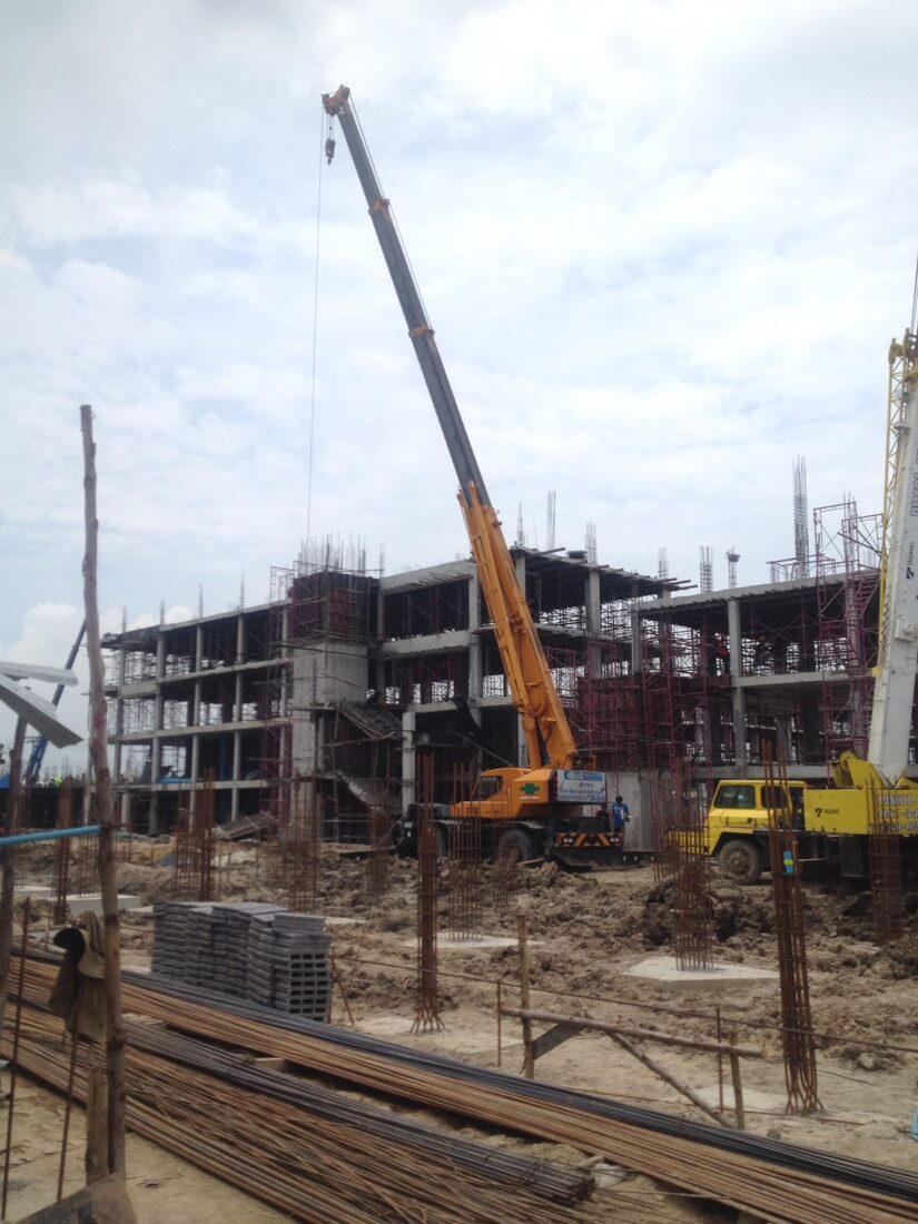 เครนล้อยาง BIG MACHINE TRADING ทำงานยกโครงสร้างที่ไซต์ก่อสร้างนิคมบางปู ท่ามกลางเสาและนั่งร้านที่ขึ้นรูปแล้ว