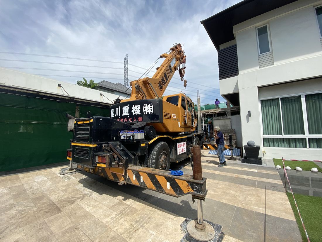 ขาช่วงล่างของเครนล้อยาง 4 ล้อ BIG MACHINE TRADING กางในลานหน้าบ้านที่แคบ งานต่อเติมบ้านหมู่บ้านบลู ลากูน 1