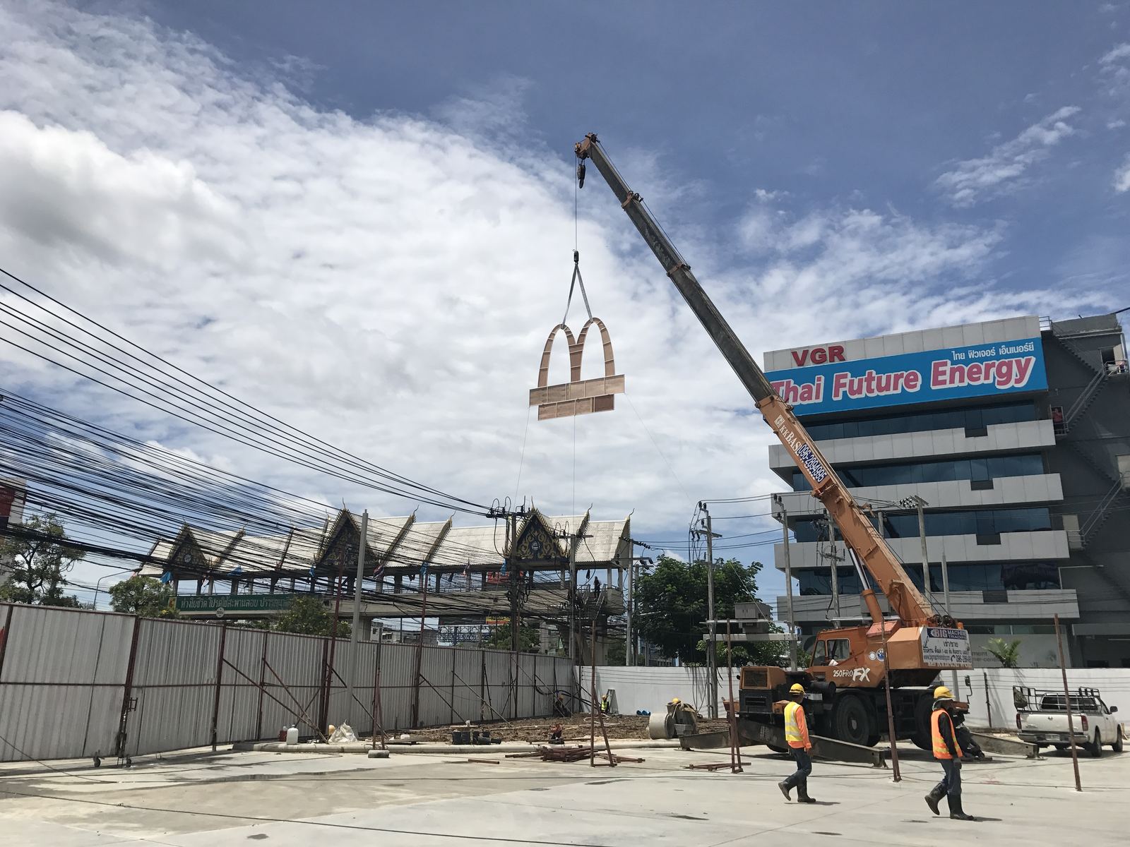 เครนของ BIG MACHINE TRADING ยกป้ายร้านฟาสต์ฟู้ดขึ้นติดตั้งบนเสาสูงริมถนน
