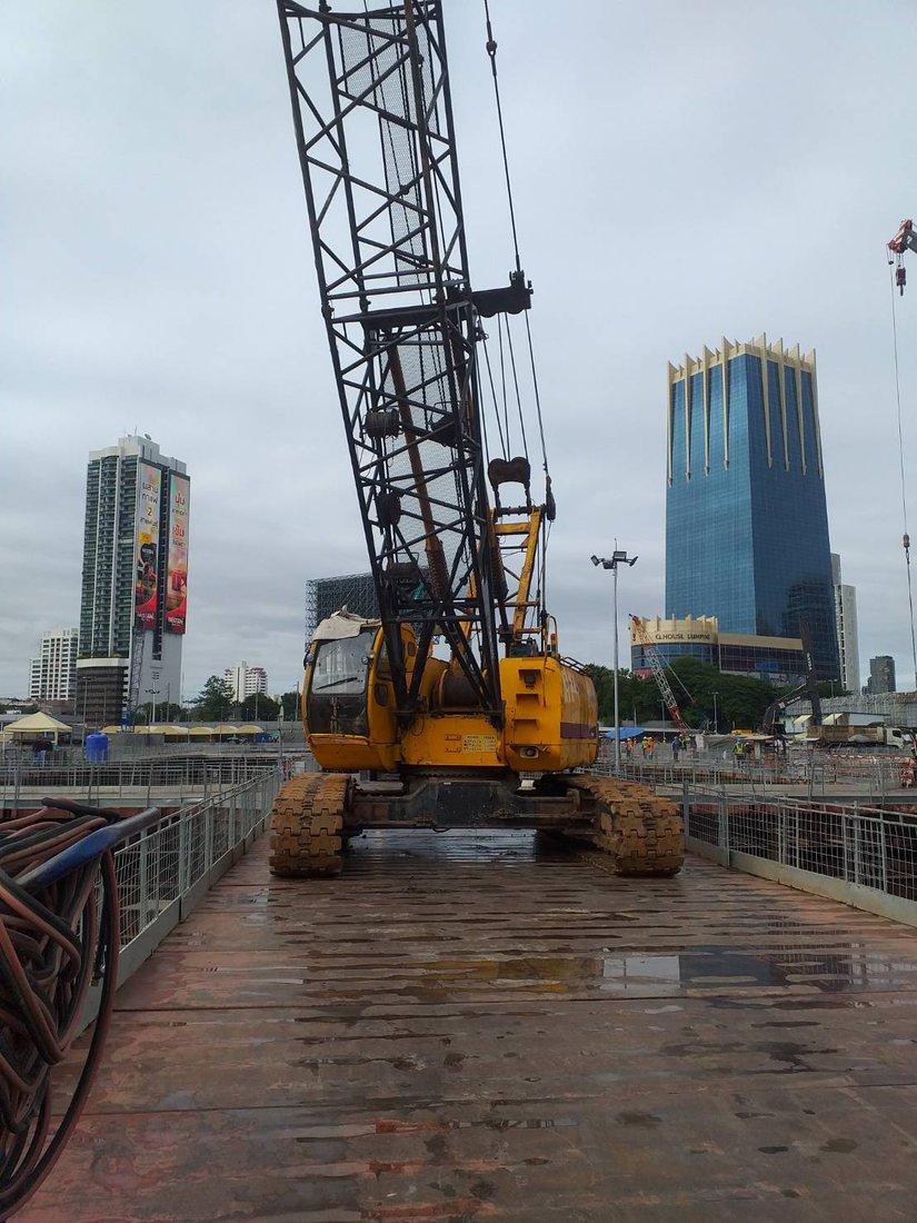 เครนตีนตะขาบของ BIG MACHINE TRADING ทำงานที่ไซต์ก่อสร้าง One Bangkok บนแท่นเหล็ก เห็นตึกสูงย่านสีลมพระราม 4 ด้านหลัง