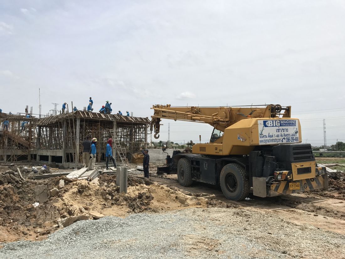 เครนล้อยาง Crevo 250 ของ BIG MACHINE TRADING ทำงานหน้าไซต์ ทีมงานควบคุมอยู่ด้านล่างและบนหลังคา