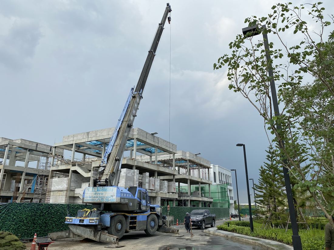 เครนของ BIG MACHINE TRADING ทำงานยามเย็นใกล้บ้าน 3 ชั้นที่กำลังก่อสร้าง ท้องฟ้าสีทึม