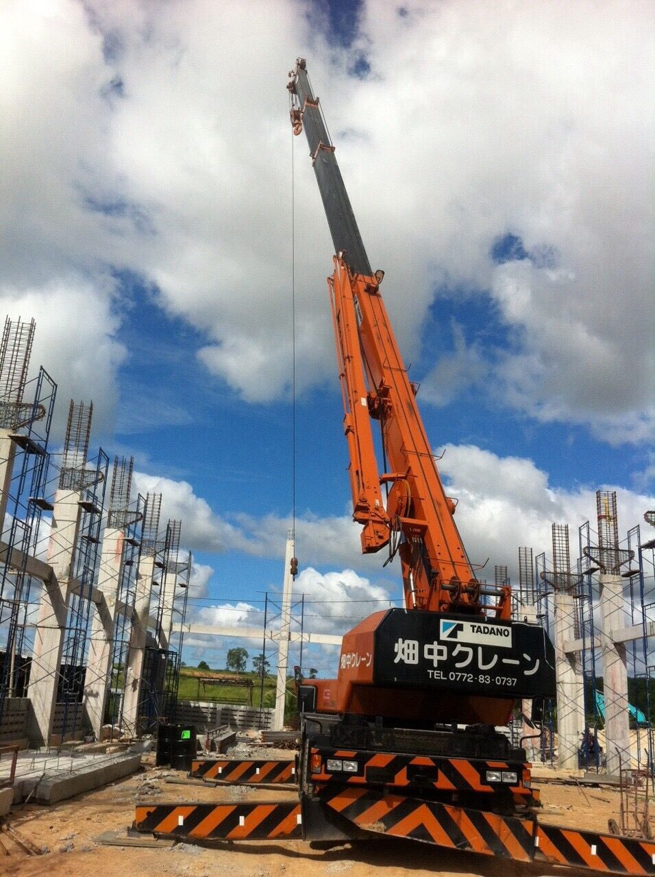 เครนล้อยาง 25 ตัน TADANO TR250M-6 ยืดบูมสูงกลางไซต์ก่อสร้างโรงกลึง CNC ระยอง ท่ามกลางเสาคอนกรีตและเหล็กเสริม