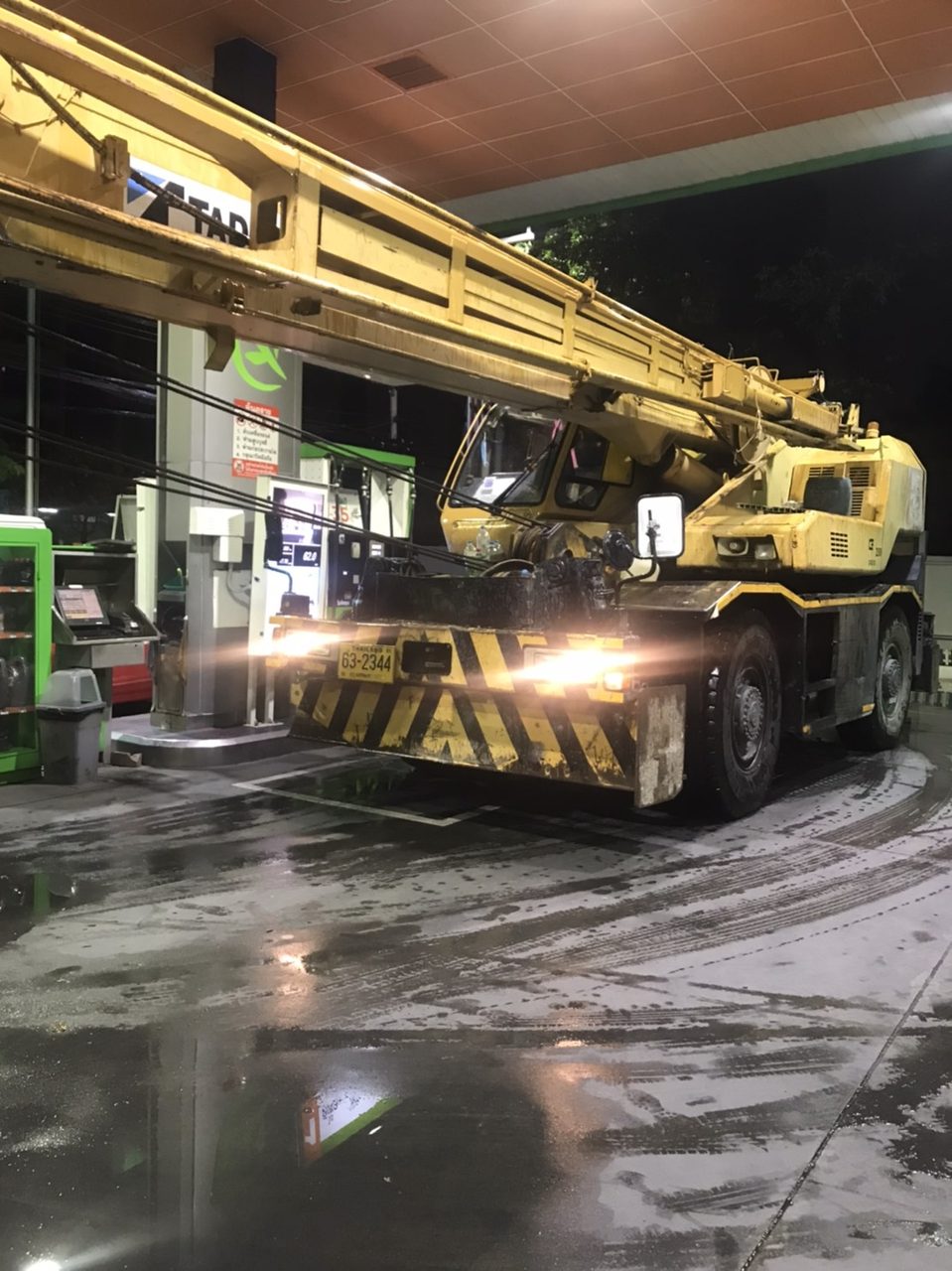 เครนล้อยางของ BIG MACHINE TRADING แวะเติมน้ำมันที่ปั๊มตอนกลางคืนขณะฝนตก ระหว่างงานก่อสร้างอาคารสูงย่านสุขุมวิท 36
