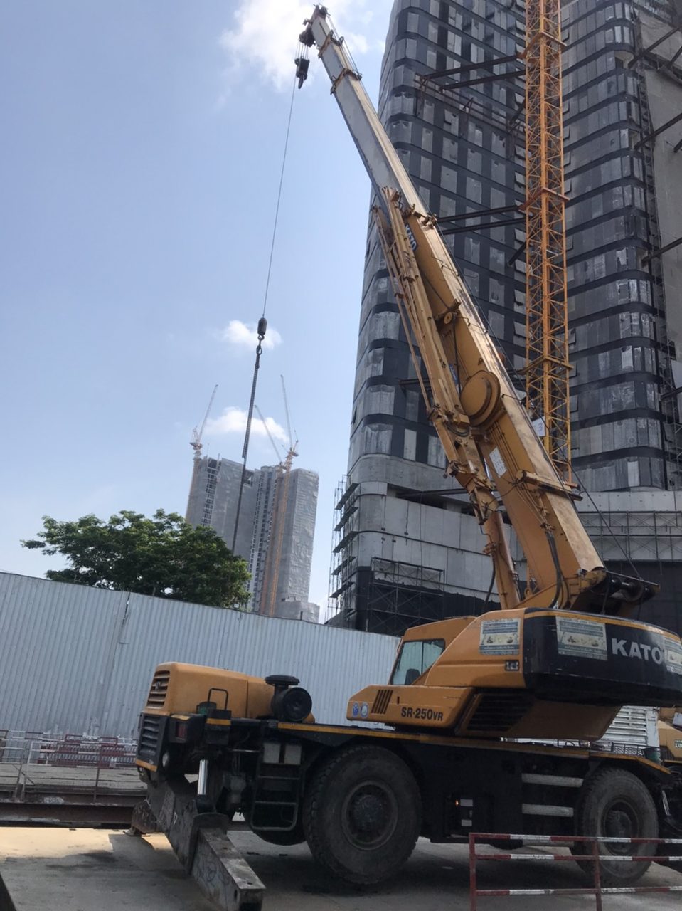 เครนล้อยาง KATO SR-250VR ของ BIG MACHINE TRADING ทำงานที่ไซต์ก่อสร้างอาคารสูงย่านสุขุมวิท 36 มีเครนหอสูงและตึกระฟ้าอยู่เบื้องหลัง