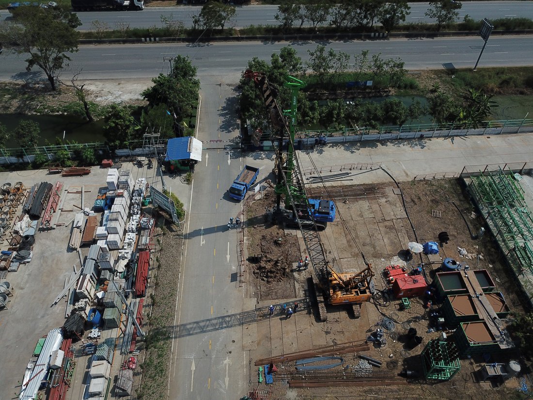 มุมสูงอีกด้านของหน้างานฐานรากป้าย SYNTEC เห็นเครนตีนตะขาบ BIG MACHINE TRADING ทำงานข้างถนนบางกรวย-ไทรน้อย