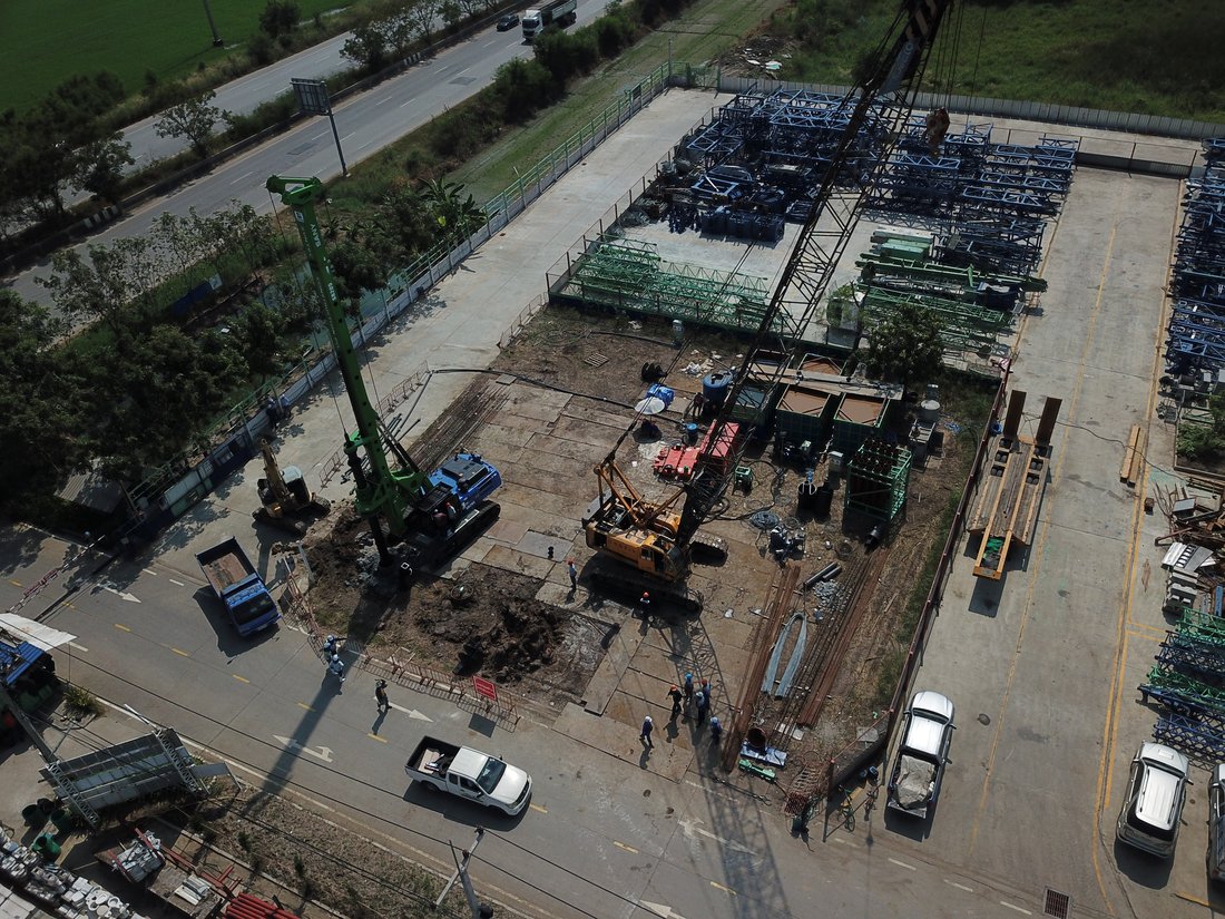 มุมสูงหน้างาน SYNTEC เห็นชิ้นส่วนโครงเหล็กป้ายบริษัทเตรียมติดตั้ง วางเรียงรออยู่ข้างพื้นที่ทำฐานราก