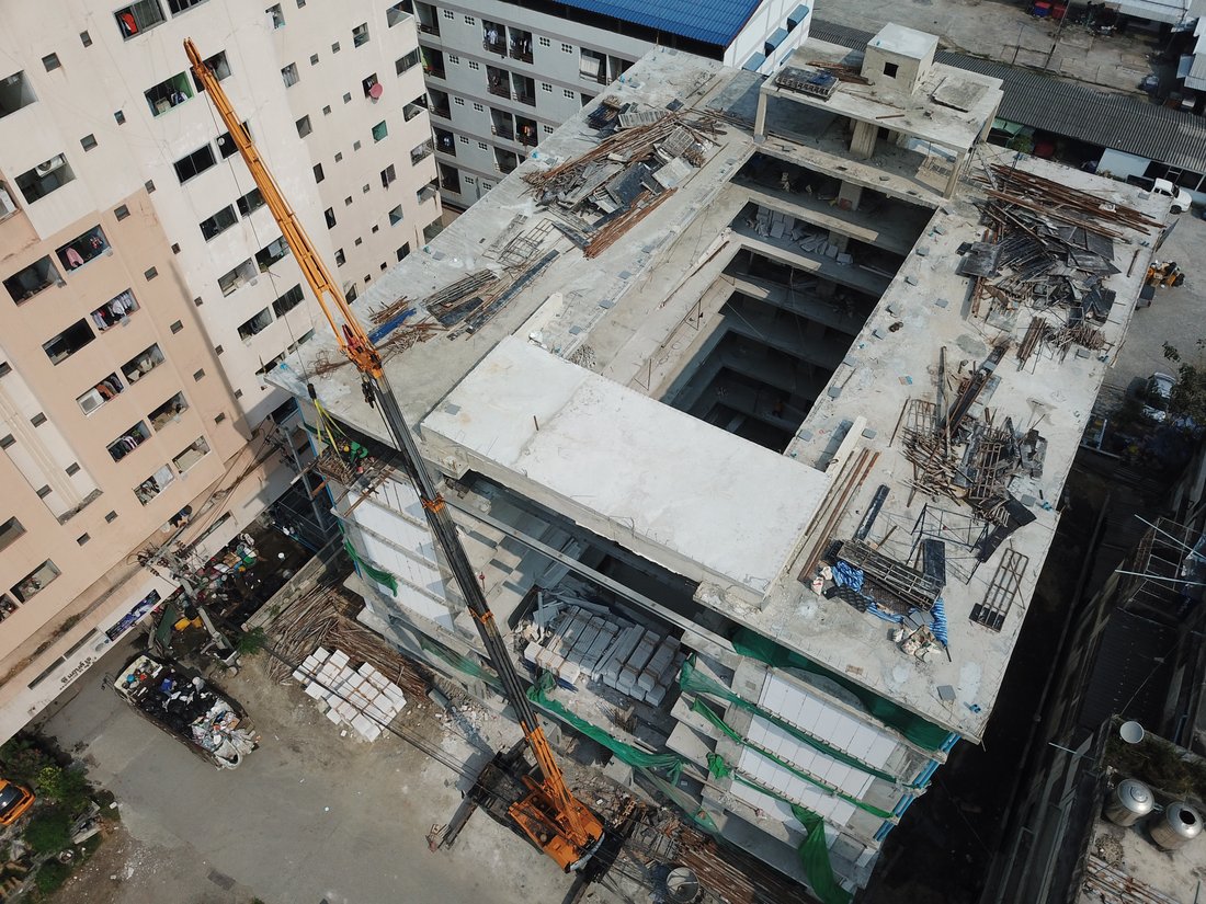 มุมสูงจากโดรน อาคาร VSK RESIDENCE ถนนกิ่งแก้ว ระหว่างก่อสร้าง มีเครนล้อยางทำงานอยู่บนดาดฟ้า ท่ามกลางอาคารที่พักอาศัยโดยรอบ