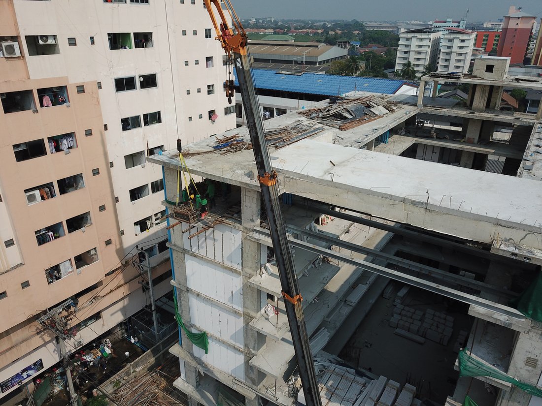 เครนล้อยาง 25 ตัน ของ BIG MACHINE TRADING ยกวัสดุก่อสร้างขึ้นชั้นบนสุดของอาคาร VSK RESIDENCE ถนนกิ่งแก้ว ระหว่างก่อสร้าง มีทีมช่างทำงานอยู่บนอาคาร