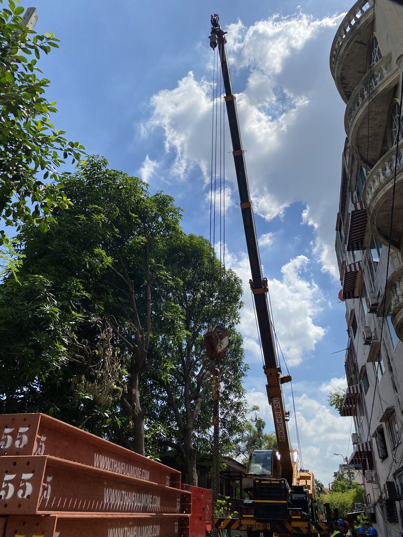ตะขอเครนล้อยาง BIG MACHINE TRADING หย่อนลงท่ามกลางต้นไม้ใหญ่ในตรอกซอยแคบริมคลอง ฝั่งธนบุรี ตลิ่งชัน-ทวีวัฒนา