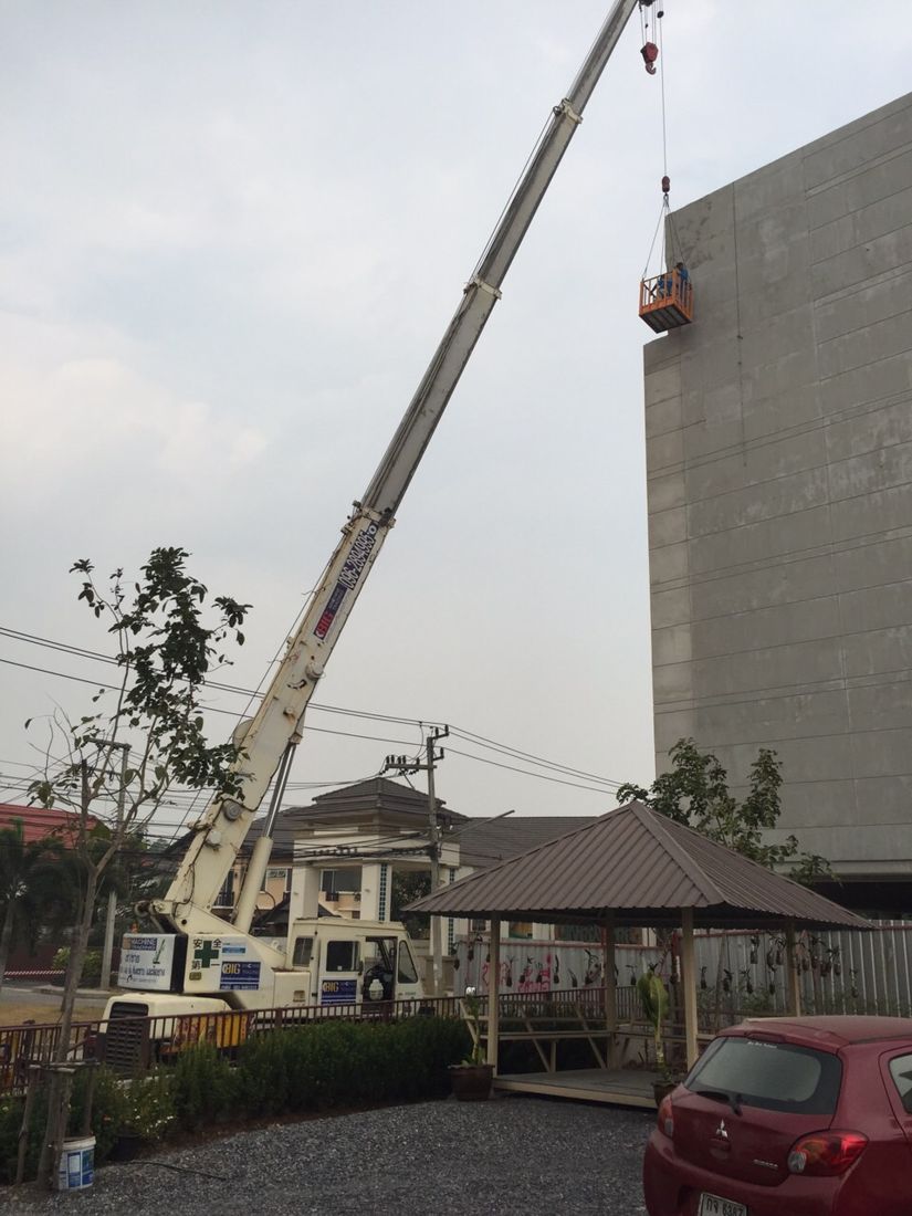 กระเช้ายกคนสีส้มห้อยจากเครน 25 ตัน ช่างทำงานใกล้ขอบบนของผนังอาคารสตูดิโอ Workpoint